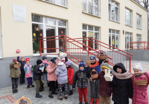 Dziecie stoją i pokazują koszyczki do których będą zbierać jajeczka