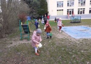 Dzieci z koszyczkami zbierają w ogrodzie jajeczka
