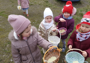 Dzieci pokazują swoje koszyczki z zebrnymi jajeczkami