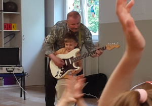 Chłopiec gra na gitarze z pomocą muzyka