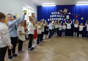Dzieci z kwiatami w rękach śpiewają piosenkę
