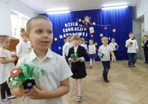 dzieci idą wręczyć kwiaty nauczycielom i pracownikom przedszkola
