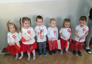 Dzieci z grupy Żabki ubrane na biało czerwono mówią wiersze na tle dekoracji święta 11 listopada