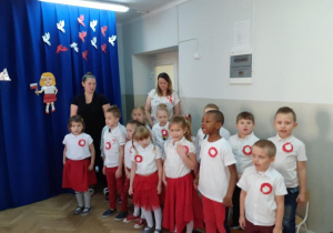 Dzieci z grupy Motylki ubrane na biało czerwono mówią wiersze na tle dekoracji święta 11 listopada