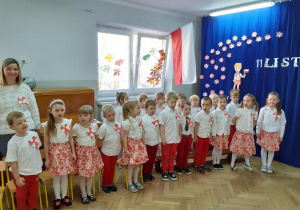 Dzieci z grupy Zajączki ubrane na biało czerwono mówią wiersze na tle dekoracji święta 11 listopada