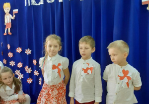 Dzieci grane na biało czerwono mówią wiersze na tle dekoracji święta 11 listopada