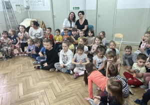 dzieci siedzą na sali gimnastycznej podczas koncertu