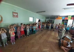 Dzieci tańczą, a "zespół muzyków" gra na instrumentach perkusyjnych.