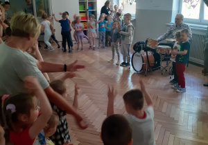 Dzieci tańczą, a "zespół muzyków" gra na instrumentach perkusyjnych.