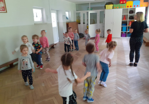 Dzieci stoją w kole i tańczą do muzyki