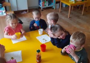 Dzieci siedzą przy stolikach i próbują owoce i warzywa