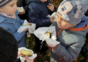 dzieci jedzą przestudzone ziemniaki prosto z ogniska