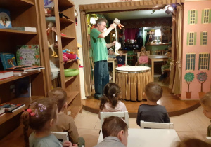 dzieci siedzą na krzesełkach i oglądają przedstawienie teatralne pt" Brzydkie kaczątko"- aktorzy którzy poruszają marionetkami