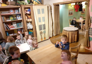 dzieci siedzą na krzesełkach i oglądają przedstawienie teatralne pt" Brzydkie kaczątko"- aktorzy którzy poruszają marionetkami