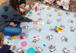 dzieci siedzą na dywanie i biorą udział w zajęciach z j.angielskiego