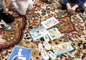 dzieci siedzą na dywanie i składają obrazek z części
