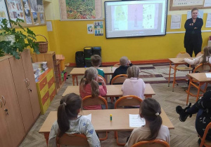 Dzieci oglądają film edukacyjny i siedzą w szkolnych ławkach