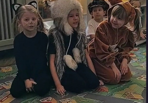 trójka dzieci siedzi na dywanie jako zwierzątka, czarny kotek, królik i wiewiórka