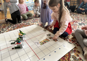 dzieci siedzą na dywanie i układają obrazki pocięte na części
