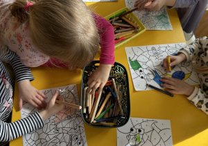 Dzieci przy stoliku kolorują według kolorów