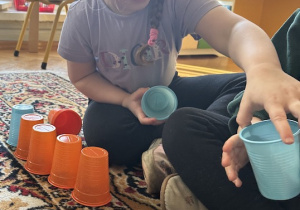 dziewczynka układa swoją wieże z kubków