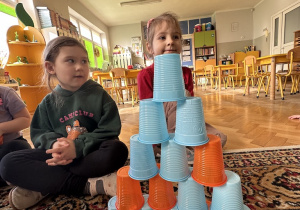 dziewczynka układa swoją wieże z kubków