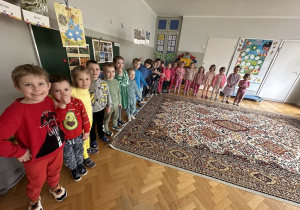 kolorowa tęcza - dzieci ubrane w kolory tęczy ustawiły się na dywanie
