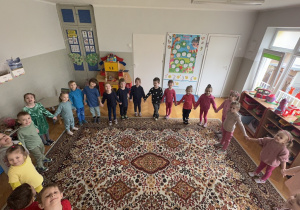 kolorowa tęcza - dzieci ubrane w kolory tęczy ustawiły się na dywanie