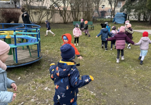dzieci udają bociany i latają po ogrodzie