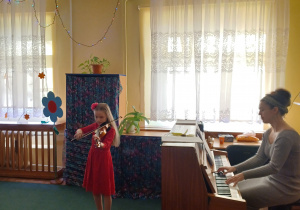 Dziewczynaka gra na skrzypcach, nauczycielka gra na pianinie