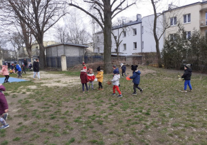 Dzieci z koszyczkami zbierają w ogrodzie jajeczka