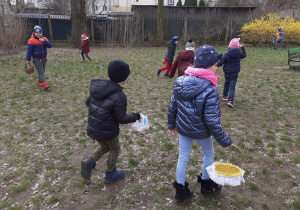 Dzieci z koszyczkami zbierają w ogrodzie jajeczka