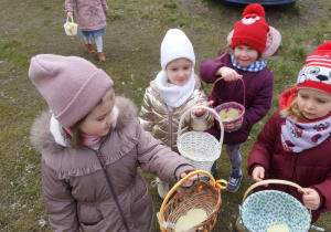 Dzieci pokazują swoje koszyczki z zebrnymi jajeczkami