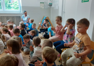 Dzieci siedzą i słuchają gry na gitarze elektrycznej