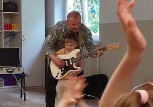 Chłopiec gra na gitarze z pomocą muzyka