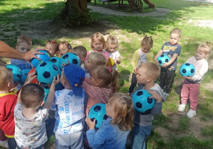 Dzieci stoją, trzymają piłkę i wykrzykuja okrzyk "Drużyna Kangura"