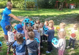 Dzieci stoją, trzymają piłkę i wykrzykuja okrzyk "Drużyna Kangura"