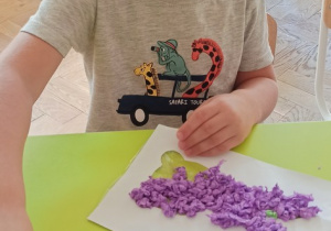 Chłopiec wykleja zajączka kuleczkami z fioletowej bibuły