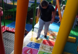 Chłopiec skacze "W klasy" na kolorowej macie