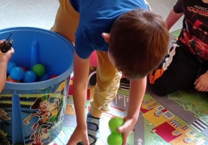 Chłopczyk segreguje piłki w zielonym kolorze