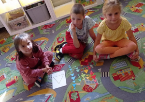 Dzieci ułożyły kolorowe trójkąty na dywanie wg wzoru