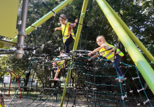 Dzieci wspinają się po linkach na zjeżdżalnie na placu zabaw