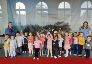 Zdjęcie grupowe dzieci na pierwszym na tle wystawy rekwizytów