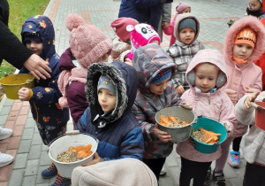 Dzieci trzymają w rączkach wiaderka z marchewkami i karmą i zaraz pójda karmić zwierzątka
