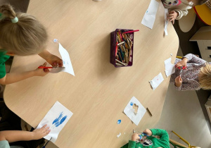 Dzieci z grupy II wycinaja narysowane oczka z kartki