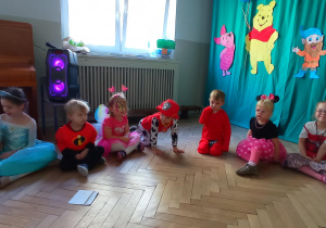 Dzieci siedzą na podłodze i słuchają zagadek Minionka