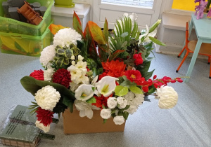 Kwiaty białe i czerwone przyniesione przez dzieci z rodzicami stoją w pudełku