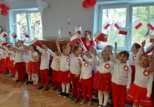 Dzieci śpiewają piosenkę i trzymają w ręku Flagi