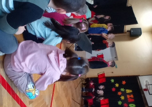 Dzieci recytują wiersz "Jesień", przedszkolaki siedzą na ławeczkach i słuchają wiersz