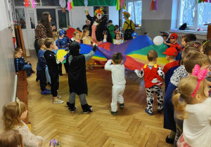 Dzieci tańczą trzymając chustę animacyjną, na chuście leżą balony